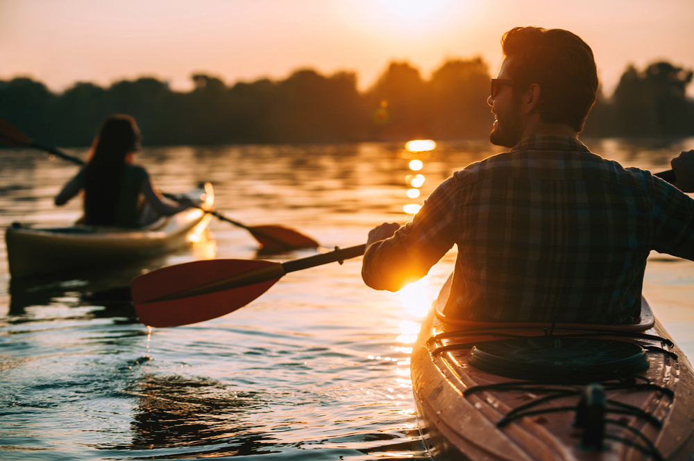 man and woman on kayaks at sunset
