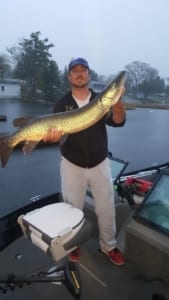 Man in fishing boat holding a large muskie